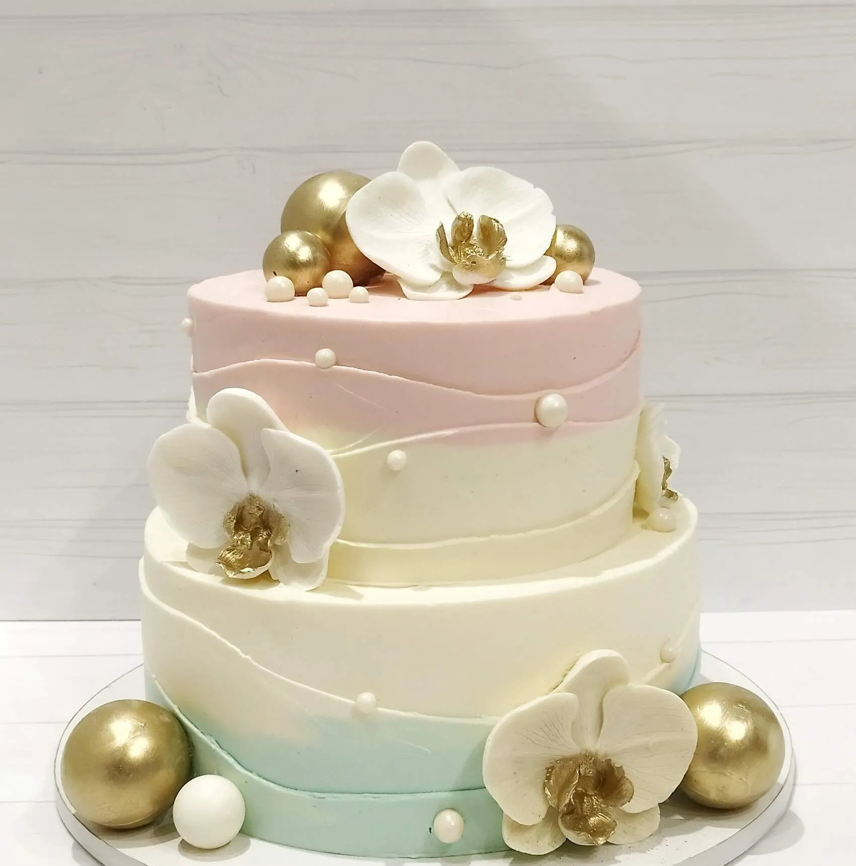 Двухъярусный праздничный торт с белыми орхидеями и золотыми сферами